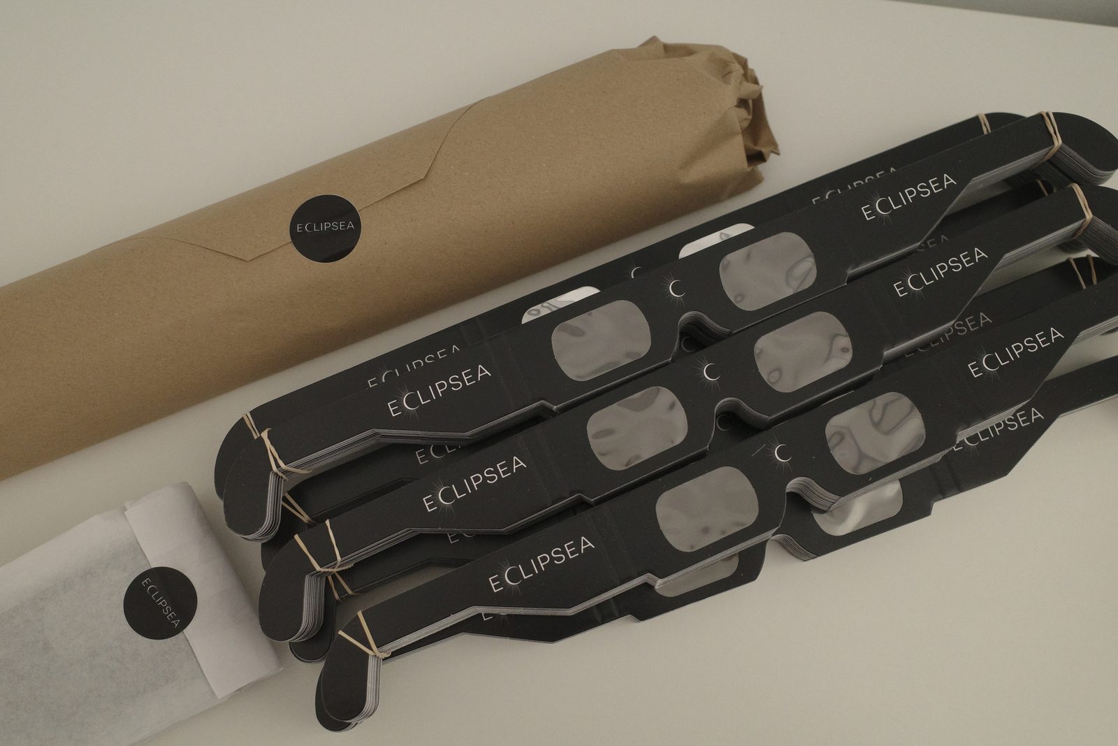 Lotes de gafas de eclipse Eclipsea certificadas, apiladas y agrupadas, junto al embalaje de envío.